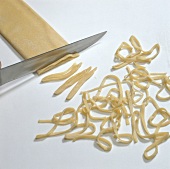 Tagliolini pasta being cut in strips with knife