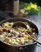 Chicken soup with noodles and sausages in casserole