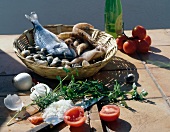 Basket of seafood beside vegetables and herbs