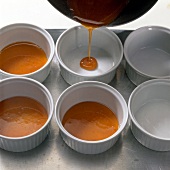 Caramel mousse being poured into ramekins