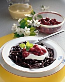 Close-up of chocolate pasta with cream and cherries on plate