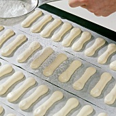 Icing sugar being sprinkled on spoon biscuits