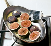 Halved figs being roasted in frying pan