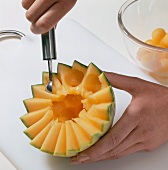 Halved melon being scooped on cutting board