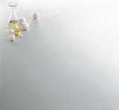Glass jar of oil and eggs on white background, copy space