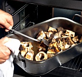 Hand mixing roasted beef stock and bone in baking tray, step 2