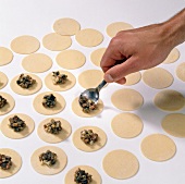 Stuffing being placed with spoon on dough circles