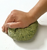 Hand kneading green dough while preparing herb pasta, step 2