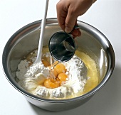 Water being added to flour and egg yolks in bowl