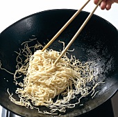 Noodles being fried in wok while preparing bami goreng pasta, step 3