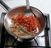 Teigwaren. Tomatensauce wird zubereitet: Sardellenfilets anbraten