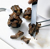 Oxtail being chopped with knife on cutting board while preparing braised oxtail, step 4