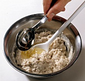 Oil being added with spoon for preparation of walnut sauce, step 2