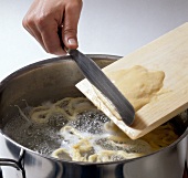 Spatzle being made by adding dough in pot of boiling water