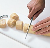 Noodle roll with filling being cut into large pieces on cutting board