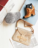 Ankle boots, cap, pile of paper and handbag on wooden flooring