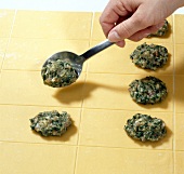 Close-up of filling being put on rectangular pasta dough with spoon