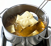 Ravioli being removed with frying spoon from pot of boiling water