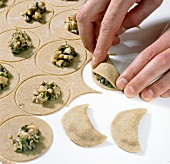 Stuffed cookie dough being sealed on white background