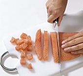 Smoked salmon being cut into cubes on cutting board