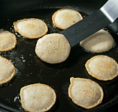 Close-up of blinis being cooked in pan till they turn golden yellow