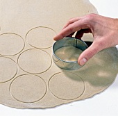 Dough being cut round with cookie cutter