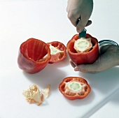 Peppers being cut and hollowed while preparing stuffed pepper, step 1