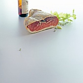 Ham and bottle of red wine on white background