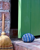 Stein mit blauem Filz beklebt als Türstopper einer grünen Tür