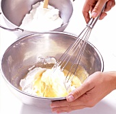 Cream being whisked with fruit cream in bowl