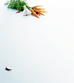 Bunch of carrots and whole clove of garlic with chilli on white background, copy space