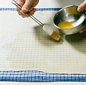 Dough sheet being greased with butter for preparing strudel