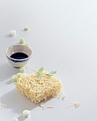 Raw Chinese noodles and sauce in bowl on white background