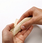 Stuffed pasta sheet being rolled for preparation of won-tans, step 2