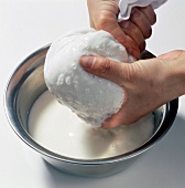 Coconut milk being squeezed out of cloth with desiccated coconut, book of exotics, step 8