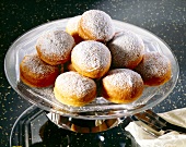 Stack of plum donuts with icing sugar on glass plate