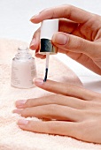 Close-up of woman applying cuticle remover on fingernails
