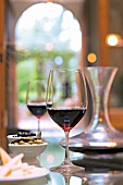 Two glasses with red wine and olives on glass table