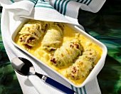 Gratin cabbage rolls in baking dish with spoon and towel
