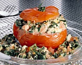 Close-up of stuffed tomato with spinach, feta cheese and almonds on glass plate