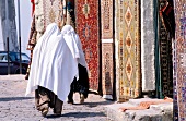 Rear view of two women wearing veils walking in carpet market, Turkey