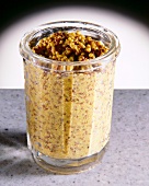Close-up of yellow brown whole grain mustard in glass jar