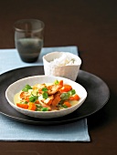 Carrot stew with parsley and chicken on plate and rice in bowl