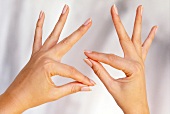 Close-up of index fingers of both hands being pressed against the thumb