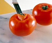 Close-up of flower buds of tomato being cut into wedge shape with knife