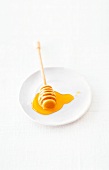 Honiglöffel mit flüssigem Honig liegt auf einem Teller