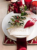 Branch of Ilex, heart shaped pendant and menu card lying on white plate