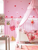 Pink children's room with canopy bed and painted heart shapes on wall