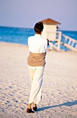 Rear view of woman with short hair wearing white outfit walking on beach