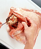 Veal breast stuffed with spoon on white chopping board